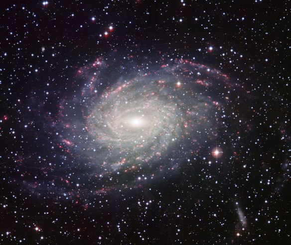 This picture of the nearby galaxy NGC 6744 was taken with the Wide Field Imager on the MPG/ESO 2.2-metre telescope at La Silla. The large spiral galaxy is similar to the Milky Way, making this image look like a picture postcard of our own galaxy sent from extragalactic space. The picture was created from exposures taken through four different filters that passed blue, yellow-green, red light, and the glow coming from hydrogen gas. These are shown in this picture as blue, green, orange and red, respectively.